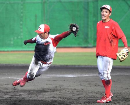 ノックの打球を飛び付いて捕球する広島・羽月。右は矢野
