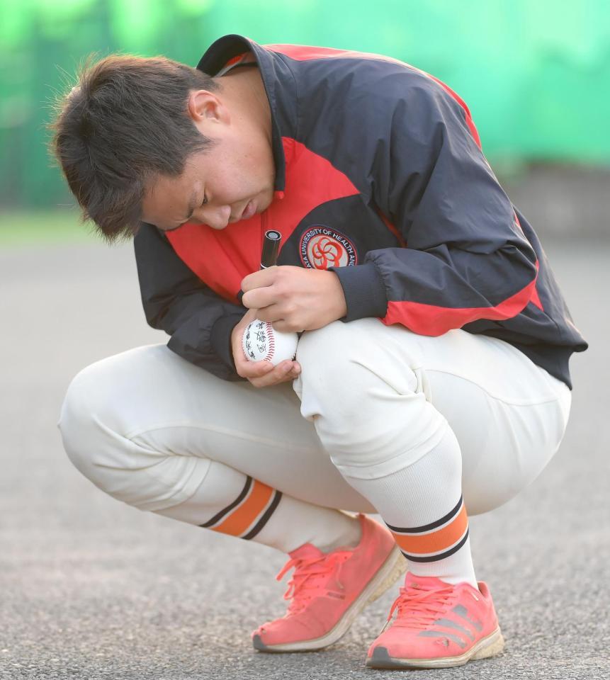 真剣な表情でボールにサインを書く阪神ドラフト３位の新潟医療福祉大・桐敷拓馬（撮影・堀内翔）