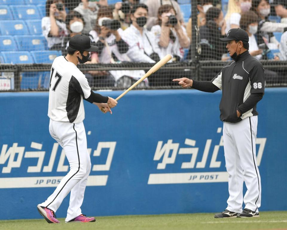 巨人戦に向けたデモンストレーションだ！試合前の練習中、森脇ヘッドコーチ（右）からノックバットを受け取り、打撃指導を受けるロッテ・佐々木朗希＝神宮球場（撮影・開出牧）