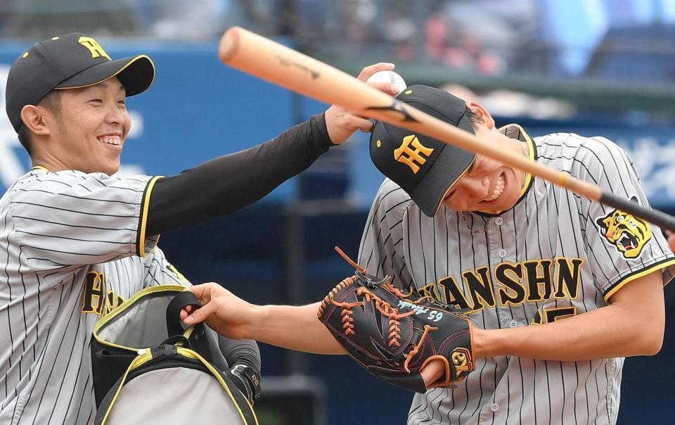 守備練習中に島田（左）から頭をたたかれて笑顔になる阪神・湯浅＝１０日、横浜スタジアム（撮影・堀内翔）