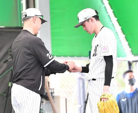ブルペンで吉井監督（左）にスライダーの握りを見せる佐々木朗（撮影・開出牧）