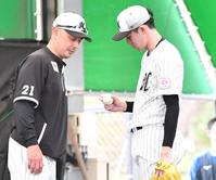 信頼関係をのぞかせる“自然体”。ブルペンで吉井監督（左）にスライダーの握りを見せる佐々木朗（撮影・開出牧）