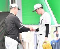 ブルペンで吉井監督（左）にスライダーの握りを見せる佐々木朗（撮影・開出牧）