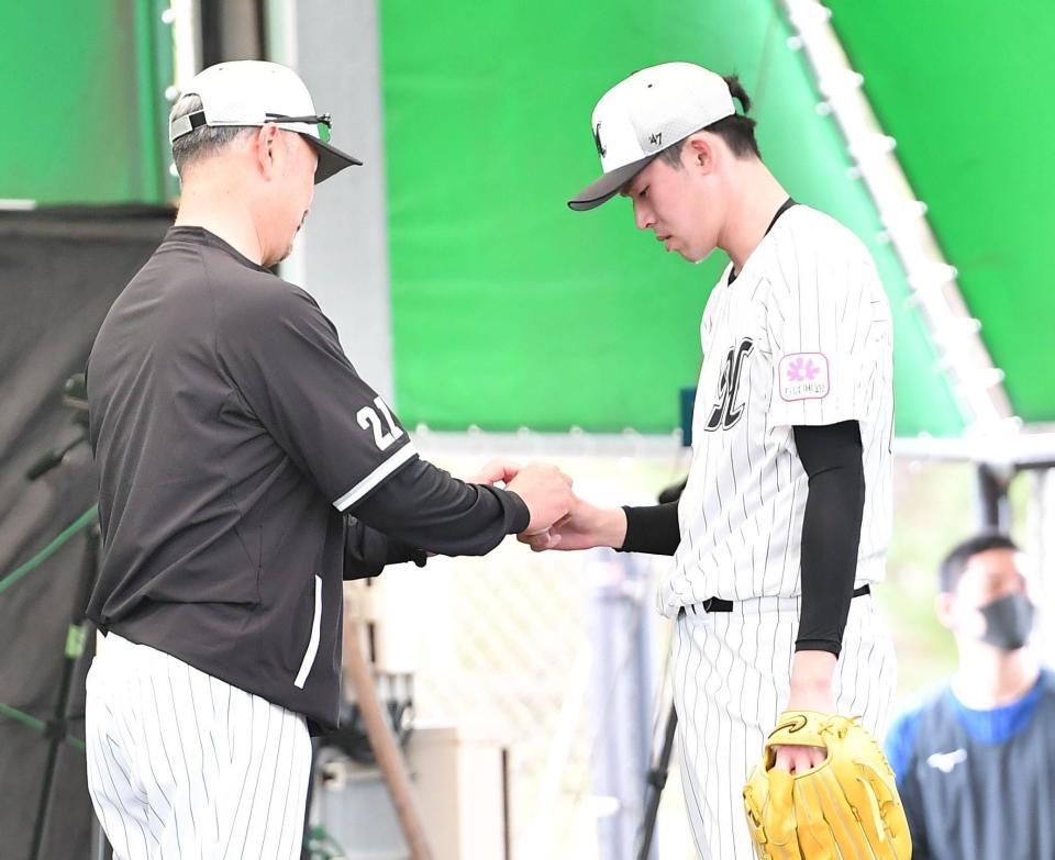 ブルペンで吉井監督（左）にスライダーの握りを見せる佐々木朗（撮影・開出牧）