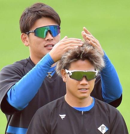福田俊（手前）のヘアスタイルをいじる日本ハム・野村佑希＝タピックスタジアム名護（撮影・伊藤笙子）