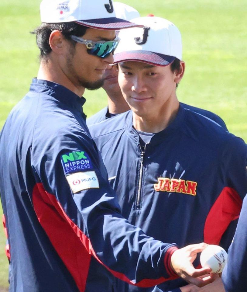 自身のサインとオリックス・宇田川優希のサインが入ったボールを披露するダルビッシュ有。右は阪神・湯浅京己＝２７日、宮崎（撮影・吉澤敬太）