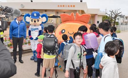 　ちーたん人気に脱帽…。キャンプ地の小学校を訪れ、北谷町のイメージキャラクター「ちーたん」（後方右）と共に登校の生徒を出迎える中日のマスコット・ドアラ。左端は北谷町の渡久地政志町長（撮影・開出牧）