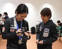 平野美宇（右）と写真を確認する木原美悠＝羽田空港（撮影・佐々木彰尚）