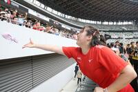 織田裕二からもらった花束を手すりから身を乗り出して投げる北口榛花＝１８日、国立競技場（撮影・吉澤敬太）