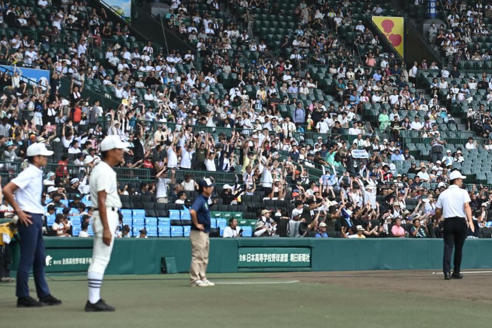 自然発生したウェーブに乗ってバンザイするバックネット裏の観客＝２３日、甲子園（撮影・開出牧）