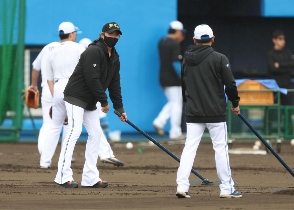 打撃練習中、グラウンド整備する新庄監督（左）＝エナジックスタジアム名護（撮影・西岡正）