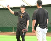 ネット越しにピッチングを見守っていた内海哲也投手コーチ（右）と言葉を交わす巨人・戸郷翔征＝１９日、那覇（撮影・開出牧）