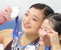 銀メダルを掲げる坂本花織の頬に涙がつたう。右は銅メダルの中井亜美＝１９日、ミラノアイススケートアリーナ（撮影・吉澤敬太）