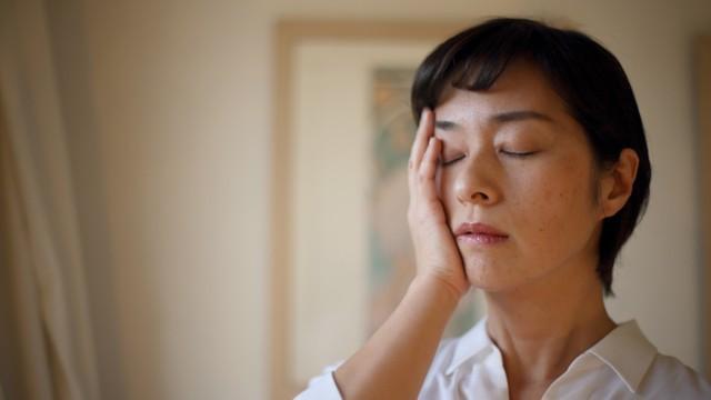 頭痛で頬に手を当てる女性(ヨコデジ/stock.adobe.com)