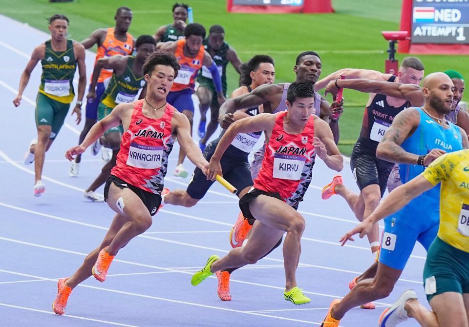 　男子４００メートルリレー予選、第２走者の柳田大輝（手前左）からバトンを受け取る第３走者の桐生祥秀（共同）