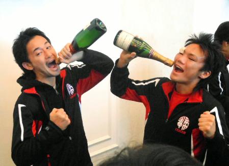 洋酒の瓶を手に“勝利の美酒”を浴びるポーズをする山中慎介（左）と五十嵐俊幸