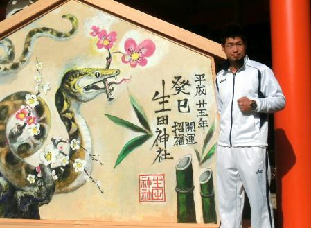 絵馬の前でポーズを取る長谷川穂積