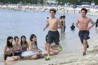 　水着姿の女性ファンに見守られながら白良浜海岸を走る井岡一翔（中央）と宮崎亮