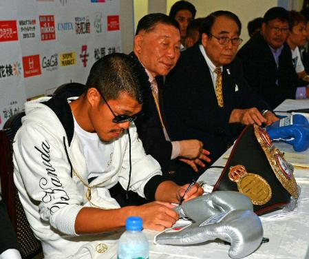 世界戦に使用するグローブに確認のサインをするＷＢＡバンタム級王者の亀田興毅＝都内のホテル（撮影・持木克友）