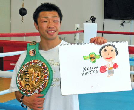 長男が書いた似顔絵を手に笑みを浮かべる八重樫