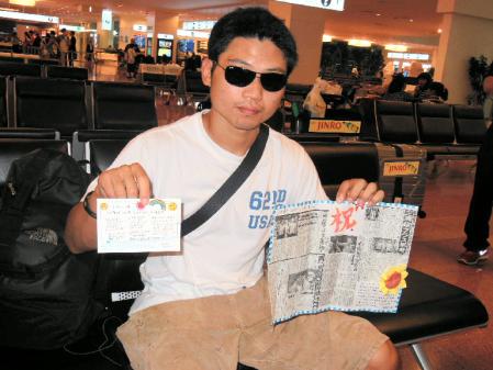 飛行機の客室乗務員から贈られた新聞の切り抜きを手にする三浦隆司＝羽田空港