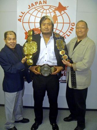 　ポーズを決める（左から）和田名誉レフェリー、王者・諏訪魔、渕取締役相談役