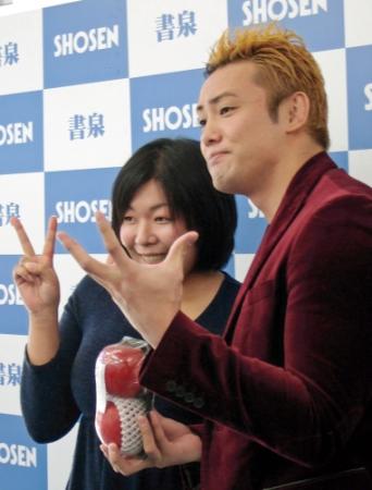 女性ファンとレインメーカーのポーズを決めるオカダ・カズチカ