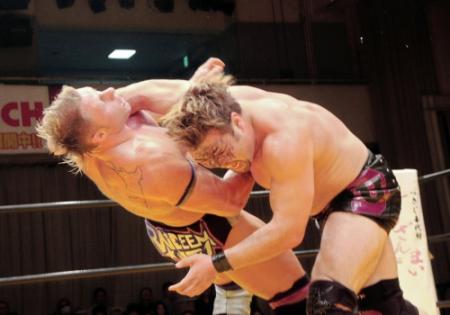 ジェームス・ライディーン（左）にラリアットをぶち込む、デーモン植田＝東京・後楽園ホール