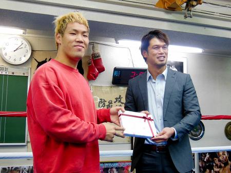 　“対戦ラブコール”のしるしとして藤本京太郎（左）にバレンタインデーのチョコレートを贈る石田順裕