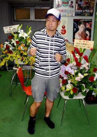 　勝利を祝い贈られた花の前でポーズを取る長谷川