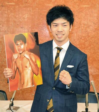 　初防衛戦の対戦相手の写真を手にポーズをとる田中恒成（共同）