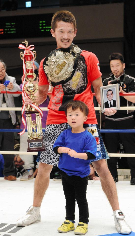 　父・雅一さんの遺影を持ち長男・豹ちゃんと笑顔の新王者・尾川堅一