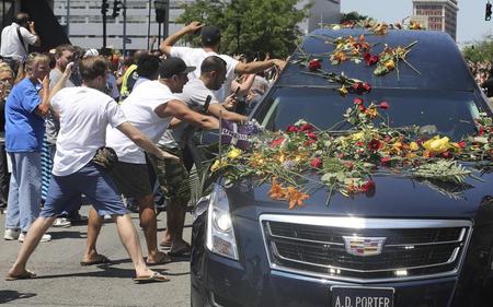 　ムハマド・アリ氏の遺体を乗せた霊きゅう車に触れようと手を伸ばす人々