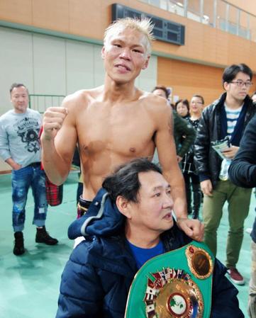 　王座を獲得し、父・進さん（下）にベルトを巻く大石豊