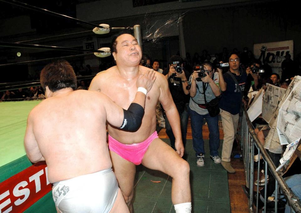 　０６年１月、百田光雄（左）の強烈なチョップに唾を吐く永源遥さん、新聞で“ガード”する観客