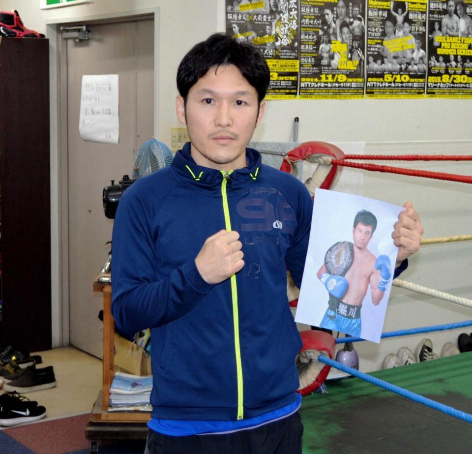 　対戦相手の堀川の写真を手にする板垣