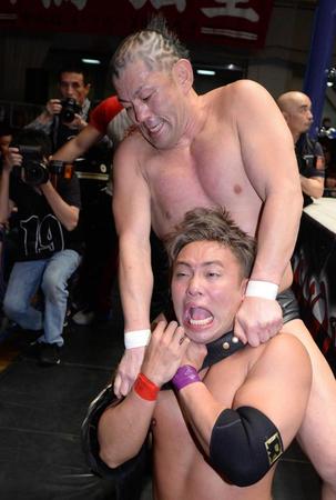 　オカダ・カズチカ（下）をベルトで絞め上げる鈴木みのる