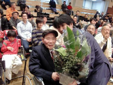 教え子の坂本博之さん（右）から花束を受け取る勝又行雄名誉会長