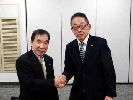 握手をする東日本ボクシング協会の渡辺均会長（右）と花形進新会長＝東京都文京区の後楽園ホール展示会場