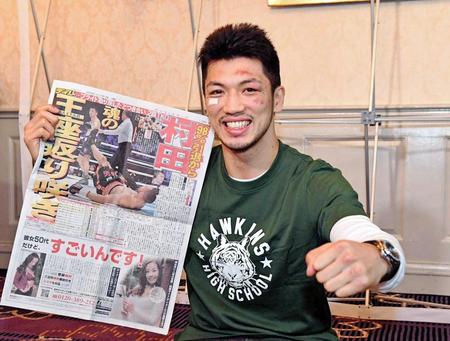 　王座奪回を伝えるデイリースポーツ紙面を手に、笑顔を見せる村田諒太