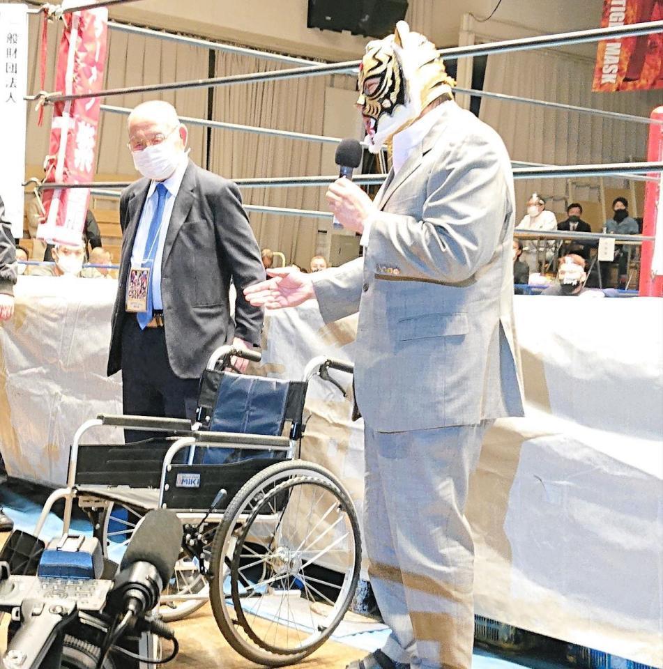 　車いすから立ち上がってあいさつする初代タイガーマスク（右）。左は新間寿会長