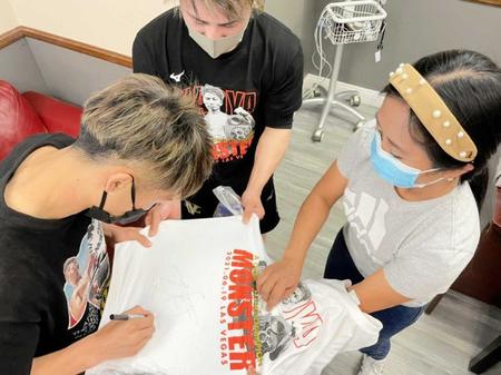 　現地の看護師（右）にＴシャツをプレゼントし、サインをする井上尚弥（左）＝大橋ジム提供