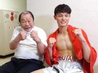 デビュー戦で勝利し、祖父の輪島功一氏（左）とファイティングポーズを決める磯谷大心