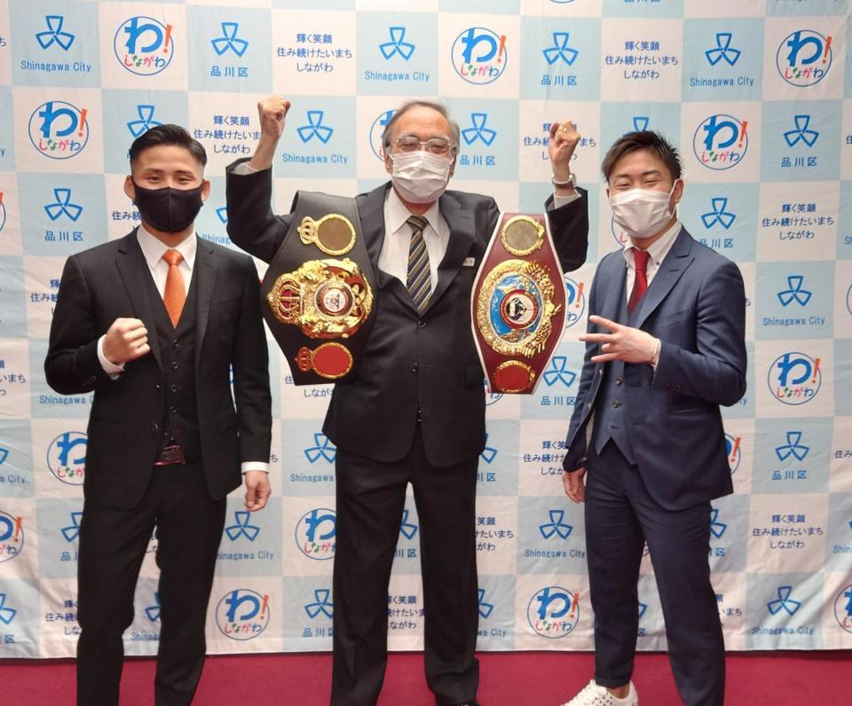 　浜野区長（中）の肩にベルトを掛けてポーズを取る京口（左）と谷口（右）