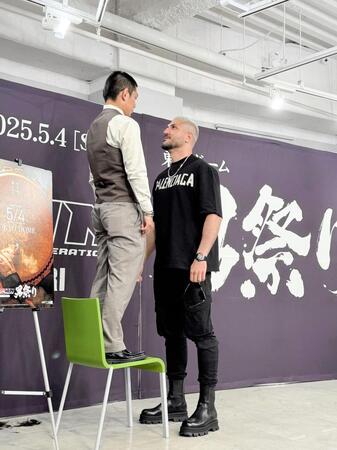 　椅子の上に立ってフェイスオフする皇治（左）とカリミアン