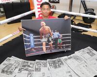 　ＴＫＯ勝利時のデイリースポーツの写真を手に笑顔を見せる武居由樹（撮影・吉澤敬太）