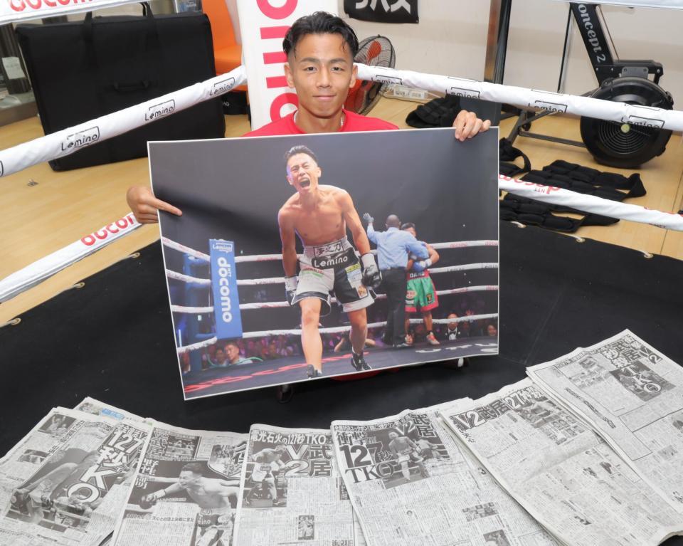 　ＴＫＯ勝利時のデイリースポーツの写真を手に笑顔を見せる武居由樹（撮影・吉澤敬太）