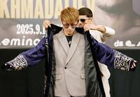 　アフマダリエフ（奥）に衣装を着せてもらう