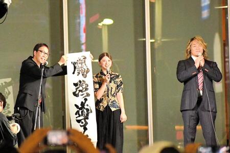 　歌舞伎町で行われた１・４東京ドーム大会の公開記者会見で「闘強導夢」と書をしたためたゲストの竹内朱莉（中央）。右は棚橋弘至