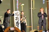 　歌舞伎町で行われた１・４東京ドーム大会の公開記者会見で「闘強導夢」と書をしたためたゲストの竹内朱莉（中央）。右は棚橋弘至